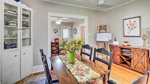 A dining area with a wooden table, chairs, a vase with flowers, a white cabinet with books, and a ceiling fan. - Georgetown Vacation Rental Close to Town Square! (Georgetown)