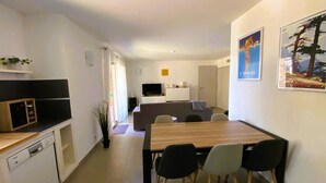A modern kitchen with a microwave, dishwasher, and a dining area with a wooden table and four chairs. - Appartement Lena. 6 pers,  piscine, 500 m plage (SAINTE LUCIE DE PORTO VECCHIO)