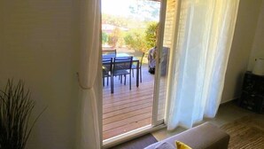 A room with a sliding glass door leading to an outdoor patio area. - Appartement Lena. 6 pers,  piscine, 500 m plage (SAINTE LUCIE DE PORTO VECCHIO)