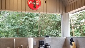 Une cuisine dotée d’un îlot central intégré, d’un évier, d’une machine à café, d’un mixeur et d’un bloc à couteaux.