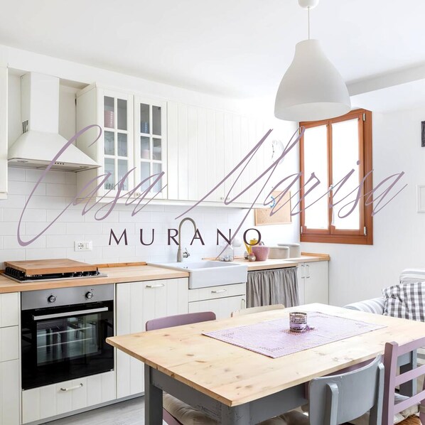 A modern kitchen with white cabinetry, a wooden countertop, and a hanging pendant light. - Casa Marisa - Quiet family apartment overlooking a square in Murano, Venice (Murano, Venezia)