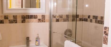 A bathroom with a pedestal sink, a glass shower enclosure, and a towel hanging on a rack.