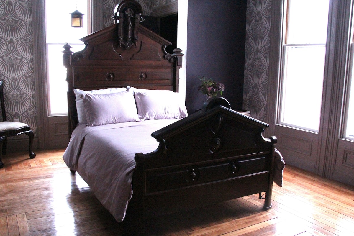 A traditional wooden bed with a headboard, a bedside table, and a chair.