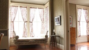 A room with a vintage-style bed, a small table with a lamp, and a dresser. - The Wedding Cake House (Providence)