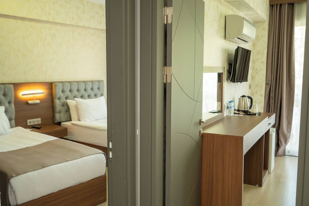 A hotel room with a bed, bedside table, lamp, and a desk with a chair.