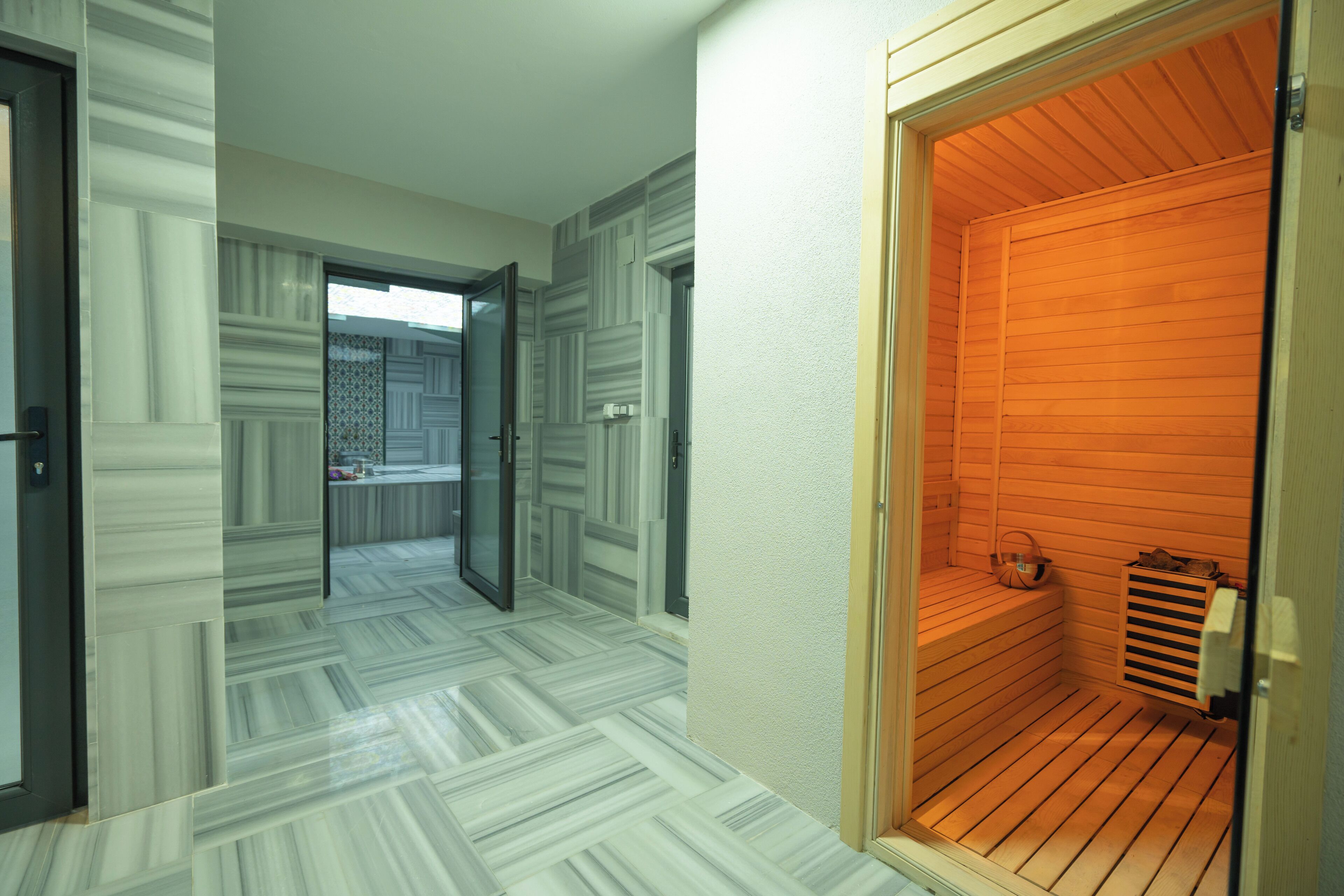 A modern interior with a wooden sauna, a patterned floor, and a glass door leading to another room.