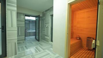 A modern interior with a wooden sauna, a patterned floor, and a glass door leading to another room.