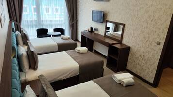 Een hotelkamer met twee bedden, een bureau met spiegel, een televisie en een raam met gordijnen.
