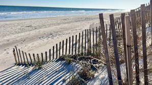 A sandy beach with a wooden fence and ocean in the background. - Beachfront Capriani Resort, Private Balcony, Ocean Pool Views, Linens Towels (North Topsail Beach)