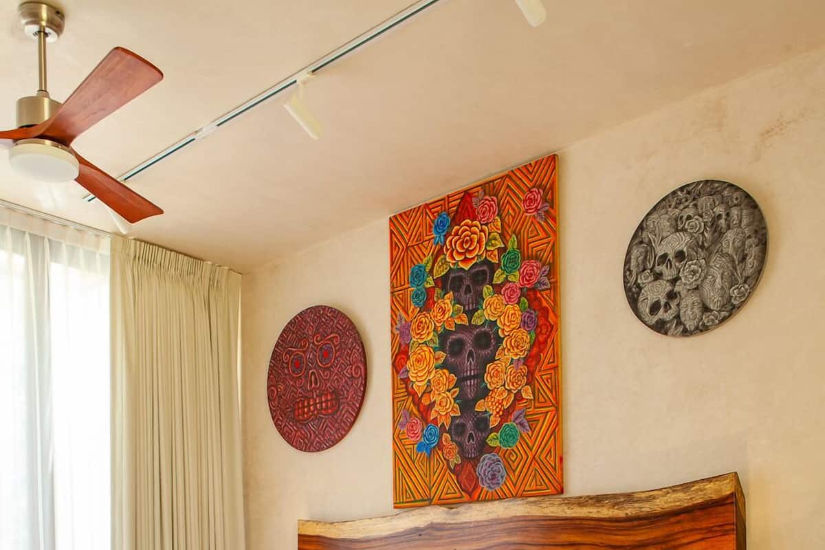 A bedroom with a wooden bed, a ceiling fan, a nightstand with a lamp, and a wall with decorative plates.