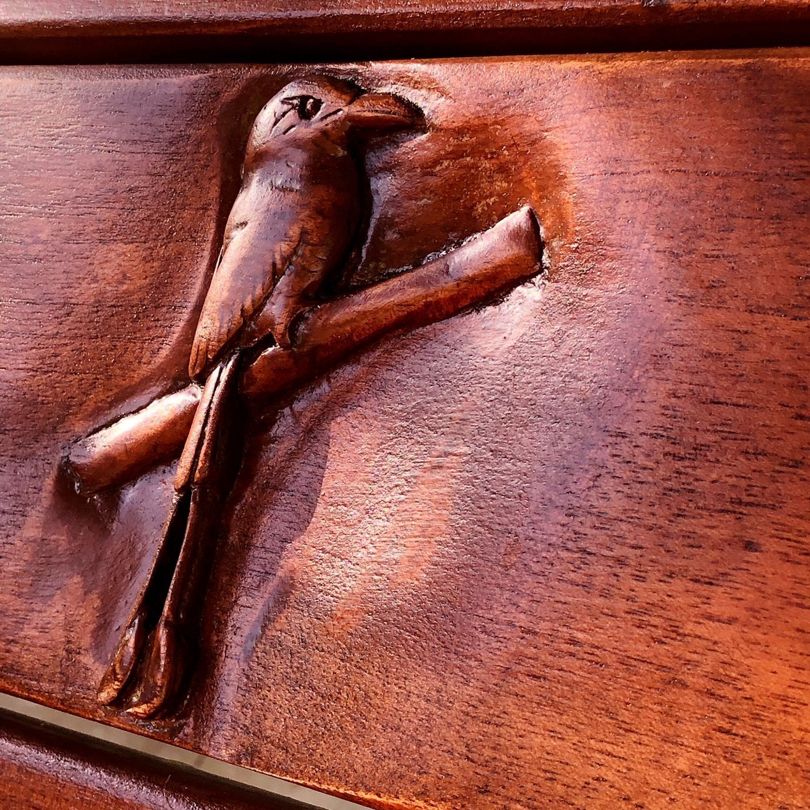 A detailed wooden carving of a bird on a surface.