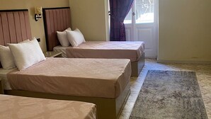 Ett hotellrum med två sängar, ett stort fönster med lila gardiner och ett golv täckt av matta.