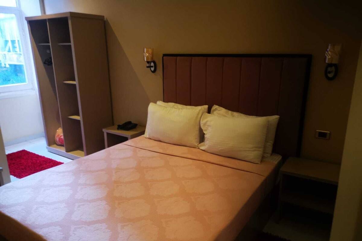 A bedroom with a bed, a wardrobe, a bedside table, and a nightstand.