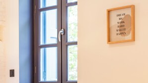Una habitación con un ventanal grande, una cita motivacional enmarcada en la pared y una moderna silla naranja con patas doradas.