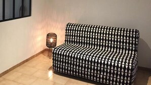 Un salon moderne avec un canapé à motifs, une lampe sur pied et une grande œuvre d’art encadrée accrochée au mur.