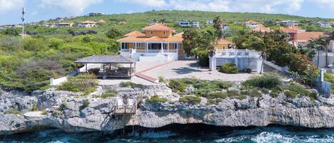 A coastal property with a rocky shoreline, a covered patio, and a view of the sea.