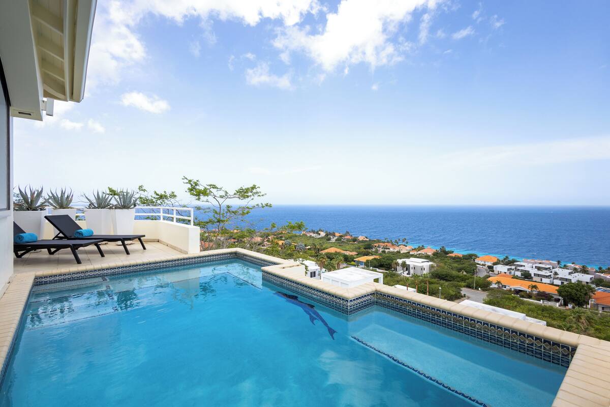 A swimming pool with a view of the ocean and a town in the background.