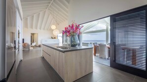 A modern kitchen with a central island, a view to the outside, and a dining area with a view. - Coral Estate Holidays (St. Marie)