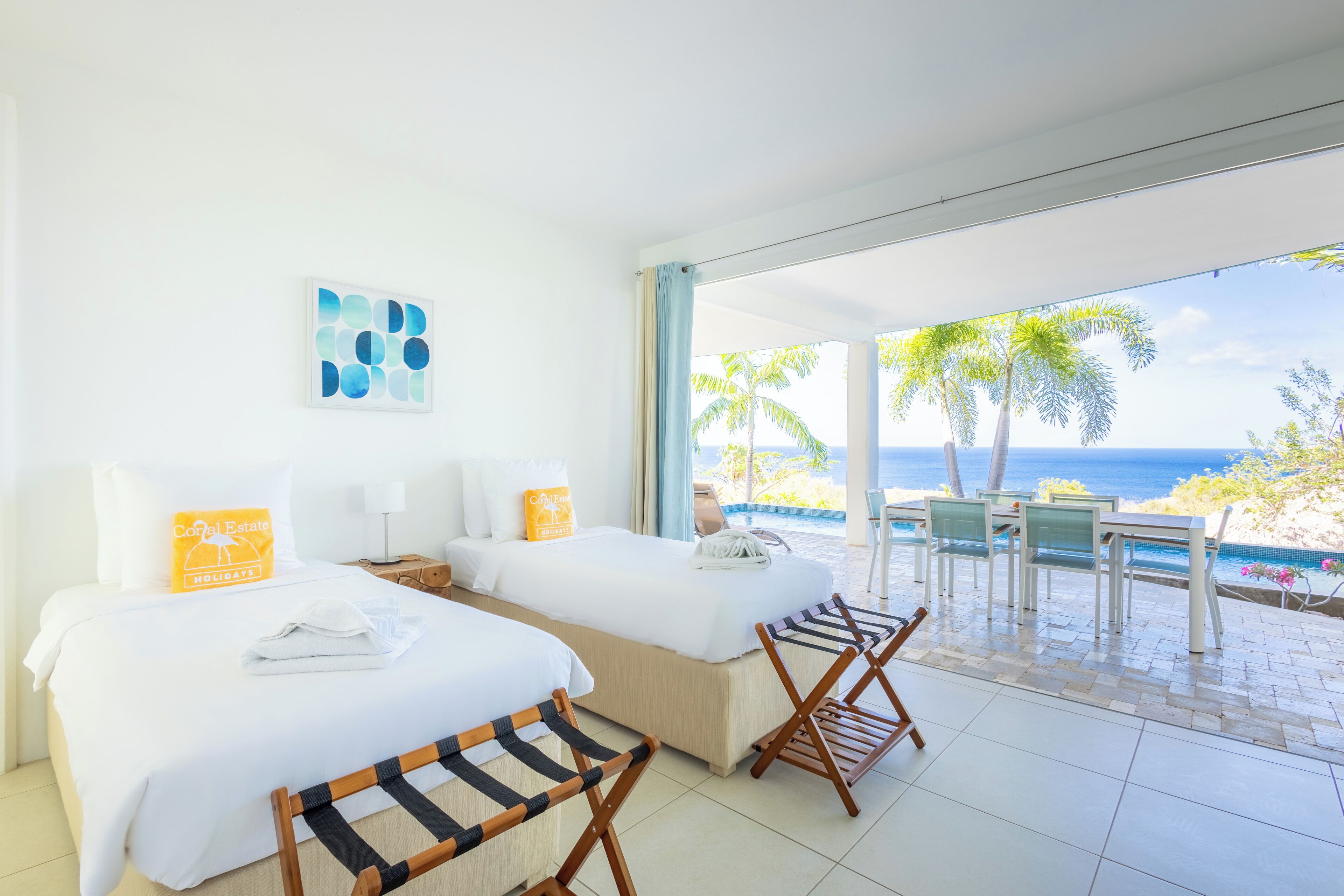 Een hotelkamer met twee bedden, een balkon met uitzicht op zee en een zwembad.