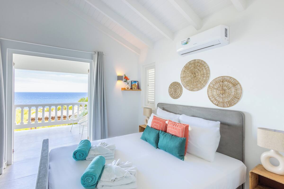 A hotel room with a bed, a balcony with a view of the sea, and decorative wall art.