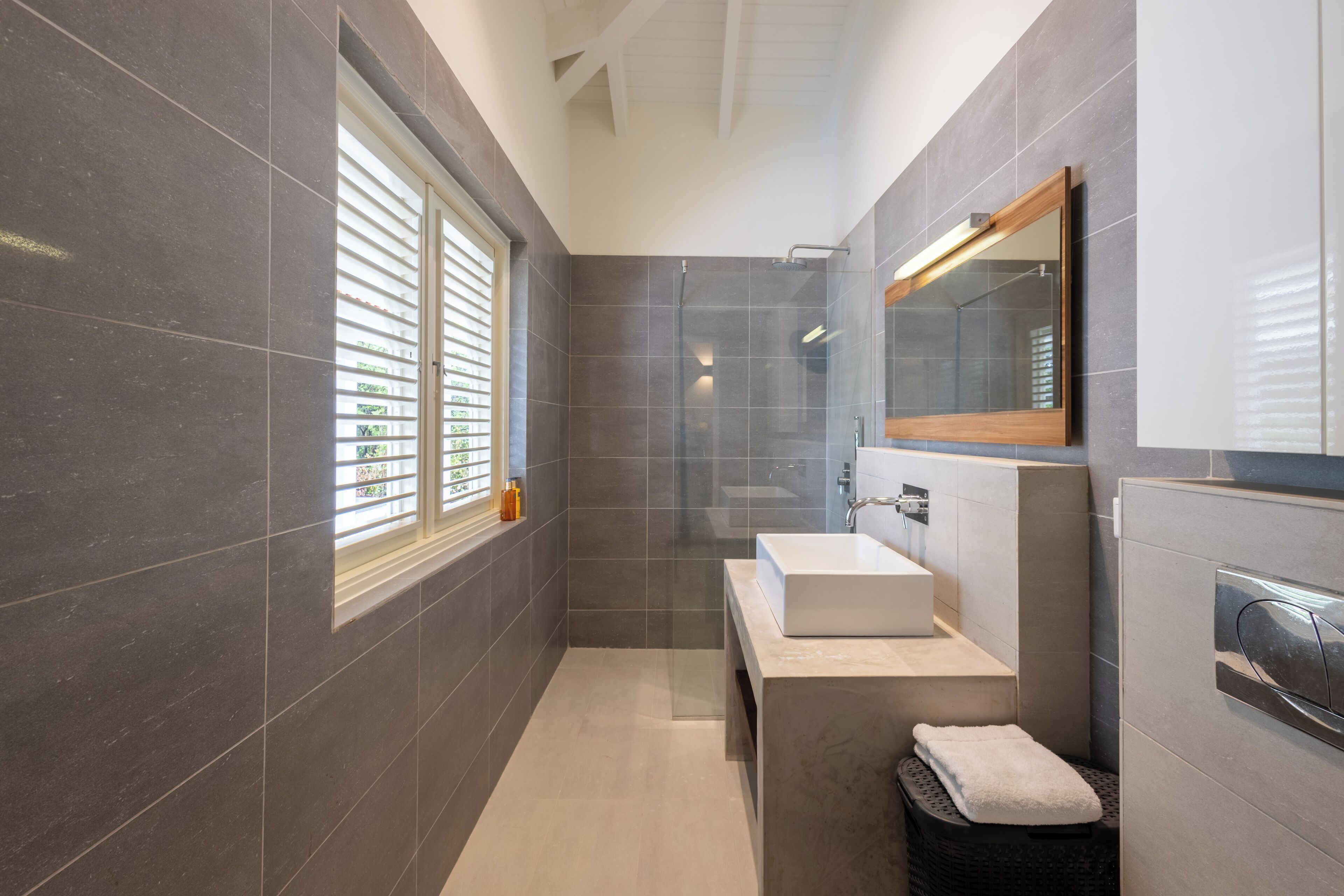 A modern bathroom with a large mirror, a sink, and a shower.