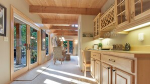 A spacious kitchen with wooden cabinets, a dining area with chairs, and large windows allowing natural light.