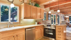A kitchen with wooden cabinets, stainless steel appliances, and pendant lighting.