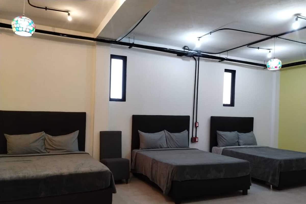 A hotel room with three beds, a small table, and a speaker.