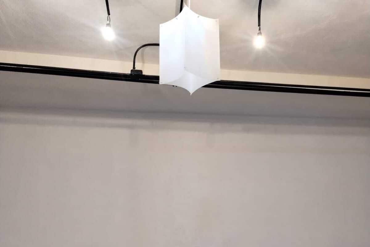 A bedroom with two beds, a nightstand, and a hanging light fixture.