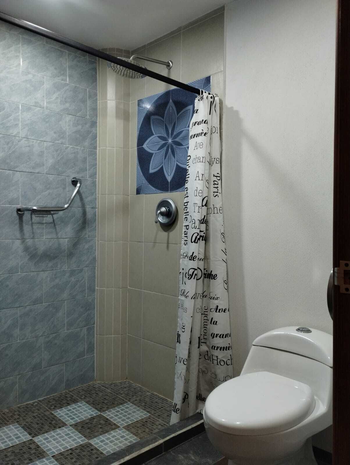 Een badkamer met douche, toilet en een greep.