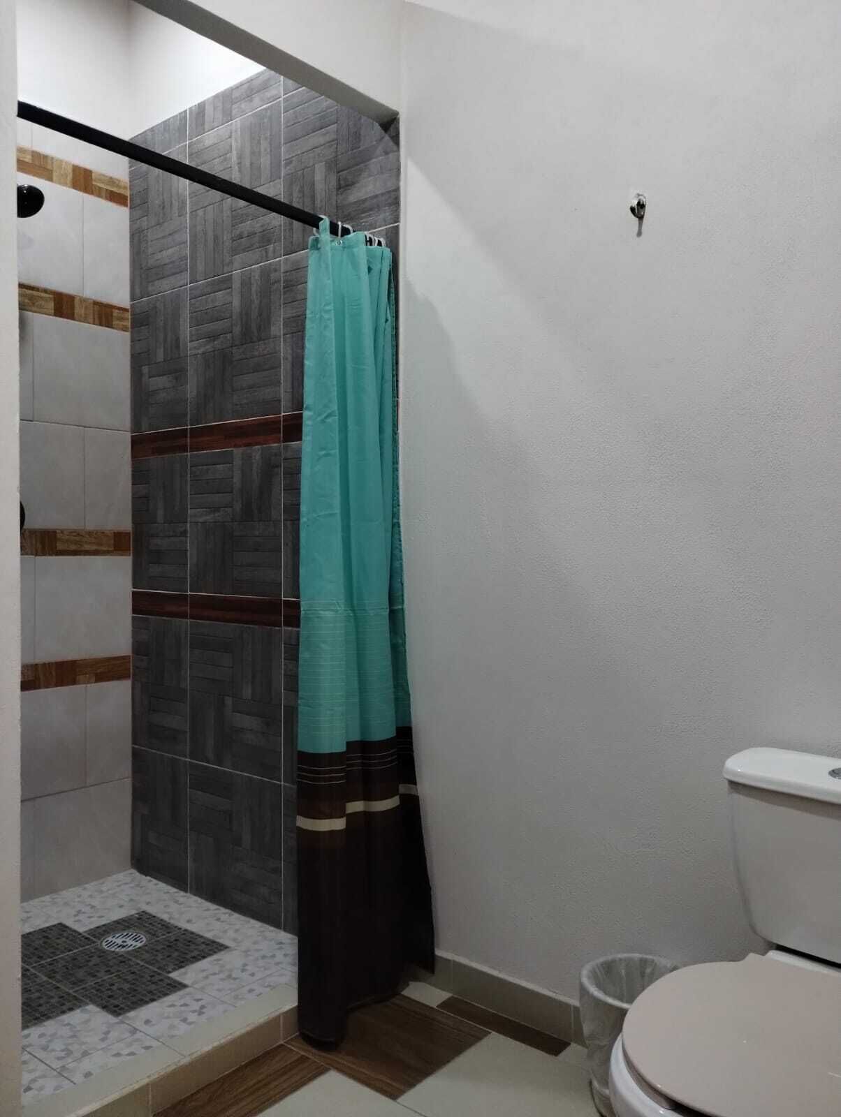 A bathroom with a shower, toilet, and tiled floor.
