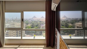 A room with large windows offering views of the pyramids and cityscape. - Grand Museum Guest House pyramids view (Giza)
