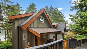 A cabin with a wooden deck, a small porch, and a view of the surrounding forest. - Ocean Views from 2 Decks! Beachfront ⎮ Amphitrite (Ucluelet)