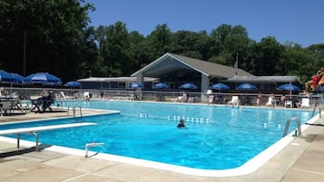 Une piscine à l’eau d’un bleu limpide, entourée de chaises longues et de parasols.