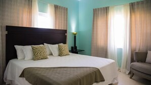 A bedroom with a large bed, a nightstand, a lamp, and a chair. - Imperial Topaz At Richmond (St. Ann's Bay)