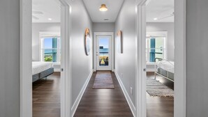 A hallway with a view to a balcony, a bed, and a door leading to another room.