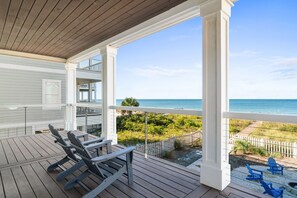 Una terraza de madera con dos sillas Adirondack mirando al mar.