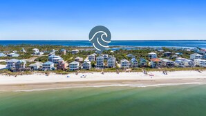 An aerial view of a coastal residential area with beachfront properties, a sandy beach, and the ocean.