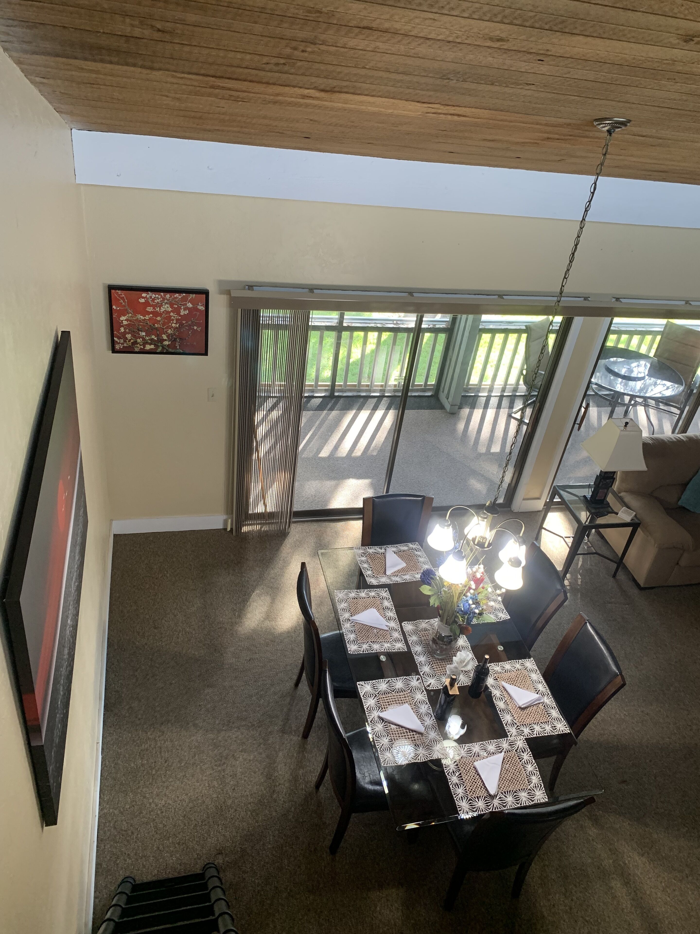 Un comedor con una mesa dispuesta para cuatro, un ventilador de techo y vistas a un patio con mesa y sillas.