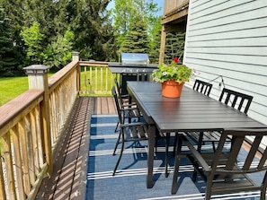 Een terras met een tafel, stoelen, een barbecue en een potplant.