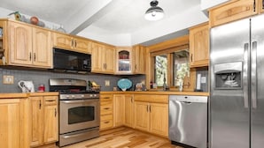 A modern kitchen with wooden cabinets, stainless steel appliances, and a tiled backsplash.