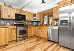 Une cuisine moderne avec des meubles en bois, des appareils électroménagers en acier inoxydable et un dosseret carrelé.