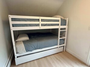 A bunk bed with a lower bunk and a top bunk, both with grey bedding.