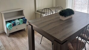 Un comedor con una mesa de madera, sillas, un reloj y una ventana con cortinas.