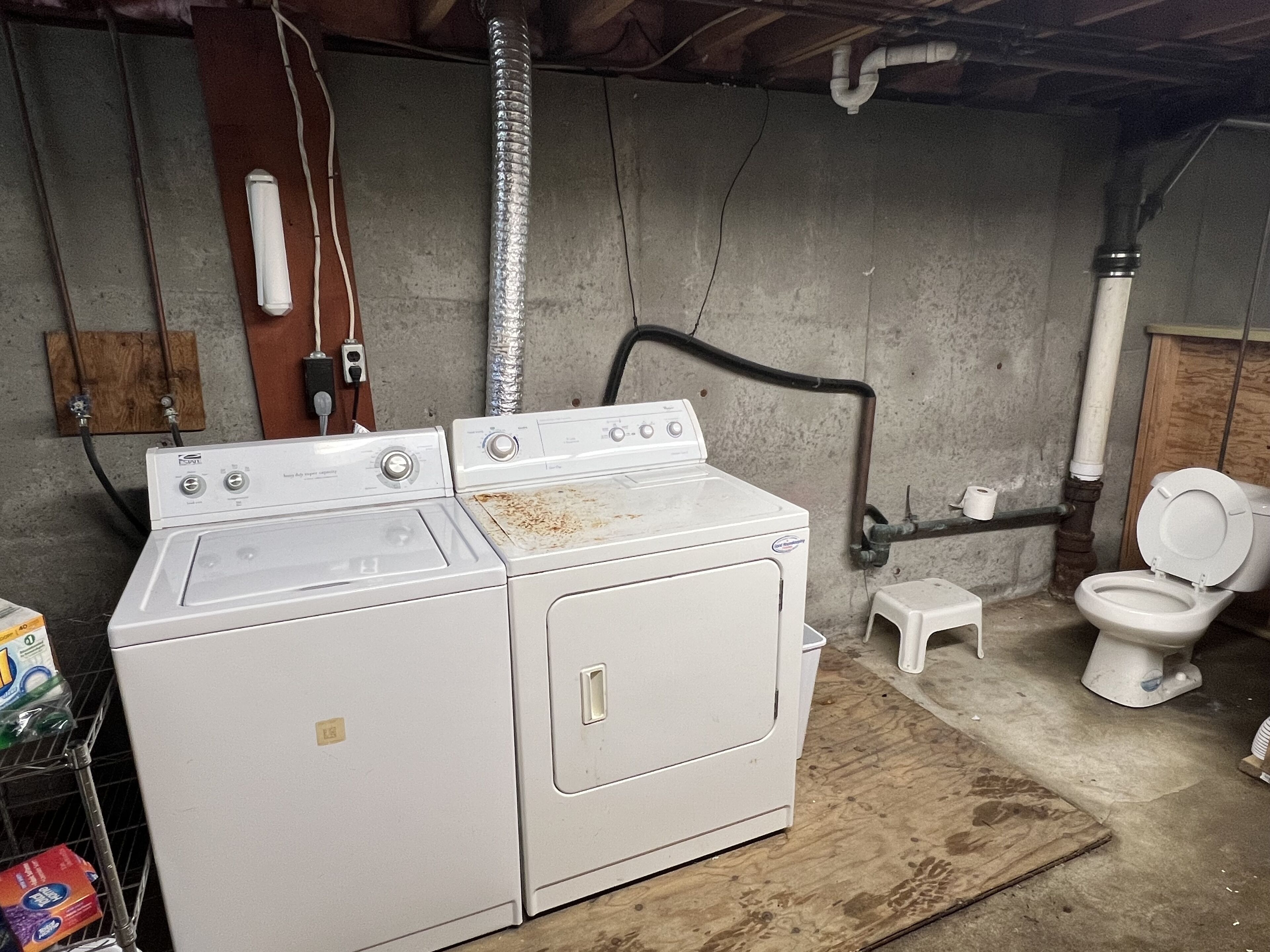 Un espace buanderie comprenant deux machines à laver superposées et des toilettes.