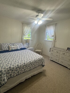 A bedroom with a bed, a nightstand, a chair, and a dresser.