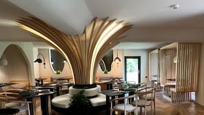 A modern dining area with a central decorative structure, wooden flooring, and contemporary furniture. - Garden Retreat  (Bran)