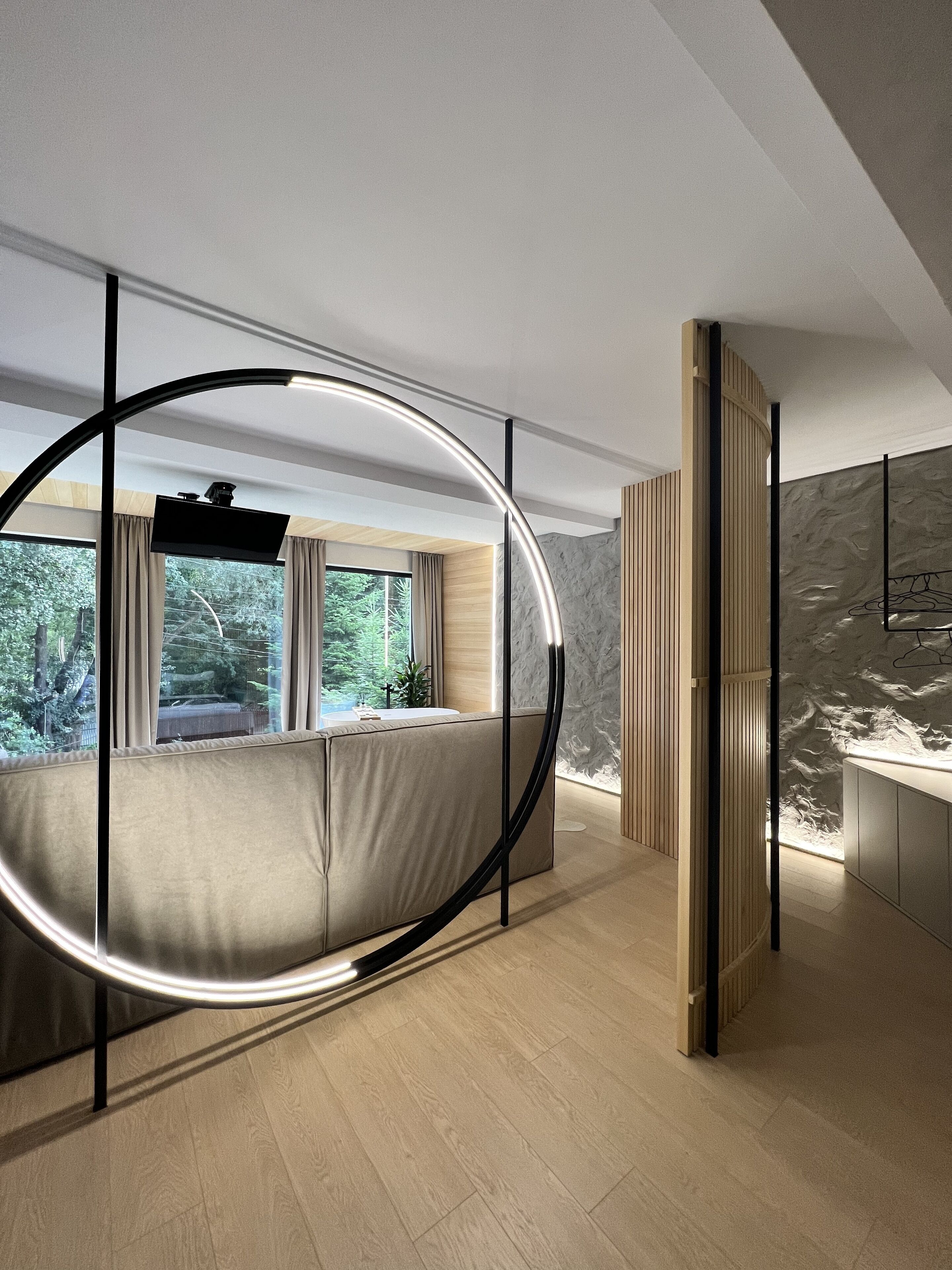 Un dormitorio moderno con estructura de cama circular, ventanas amplias y vistas a la vegetación.