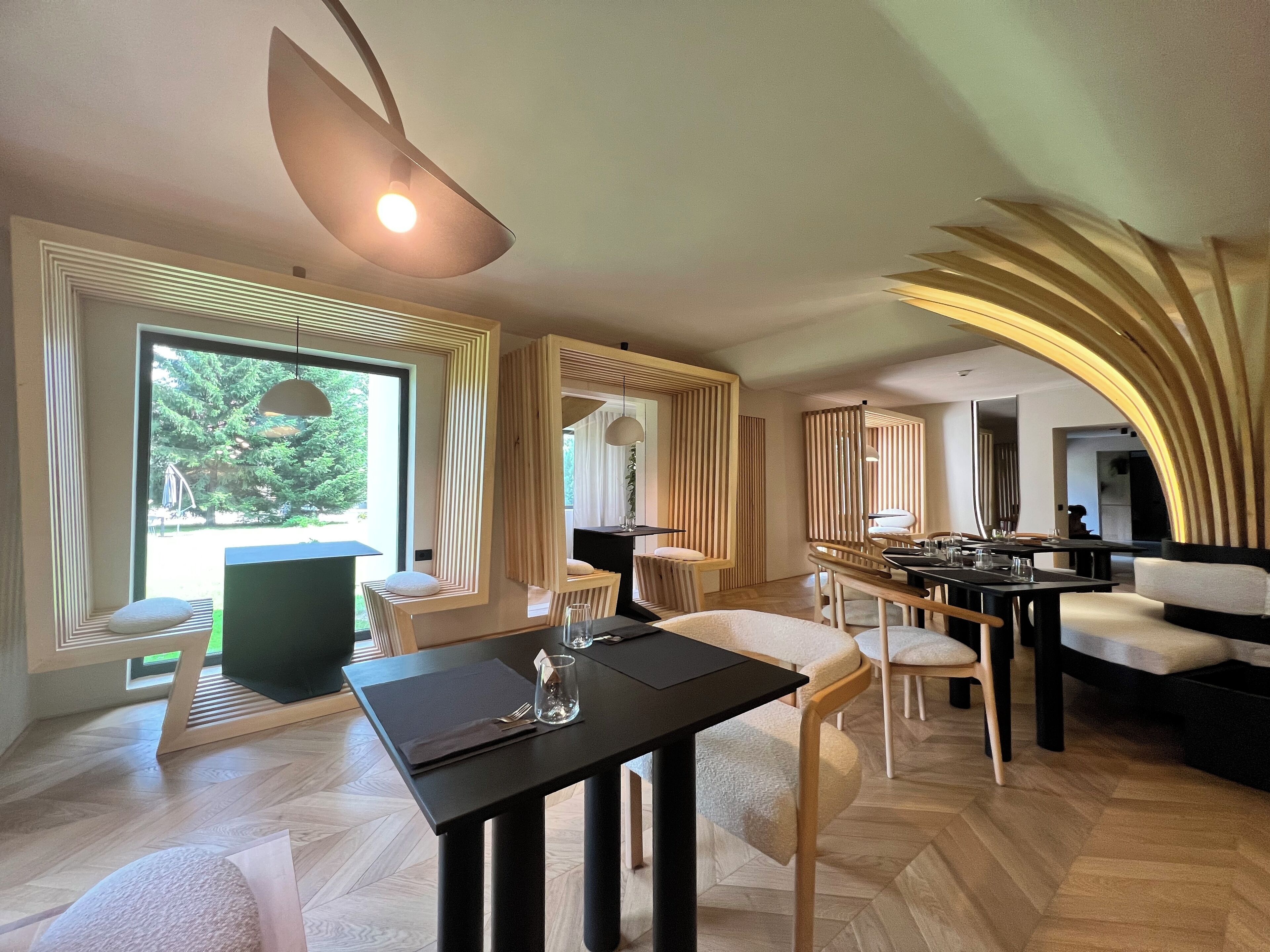 Un comedor moderno con una mesa negra, sillas blancas y un ventanal que ofrece vistas al exterior.