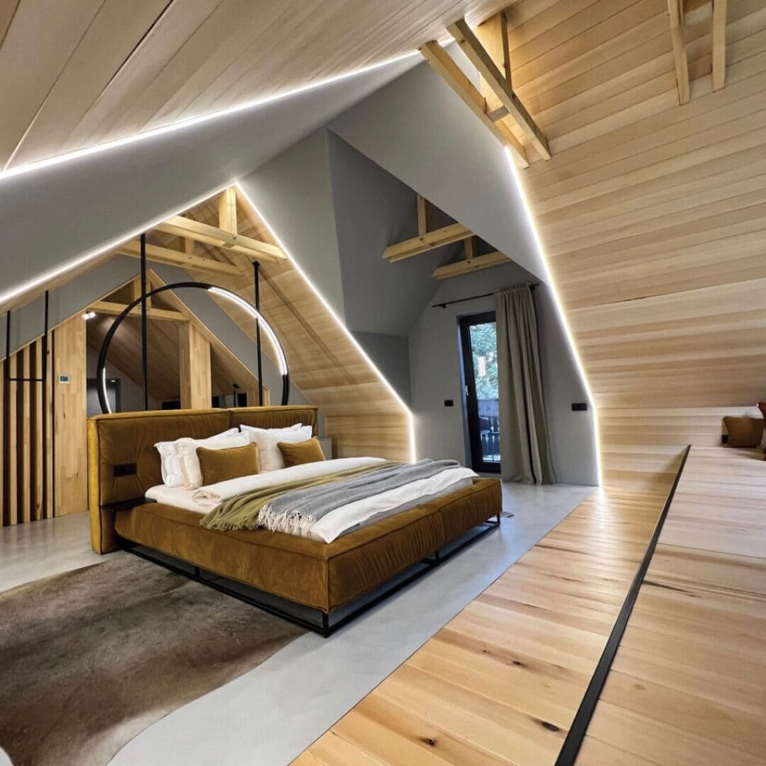 A modern bedroom with a sloped ceiling, a wooden bed, and a large window.